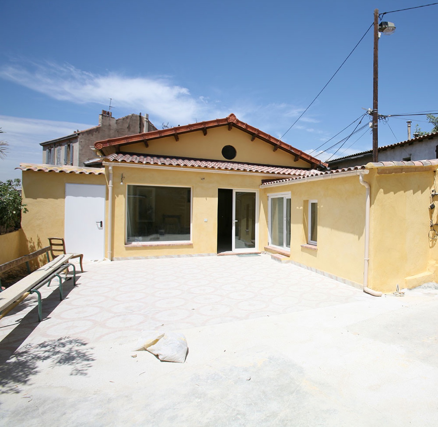 Maison jaune rénovée par JHS Entreprise, terrasse carrelée
